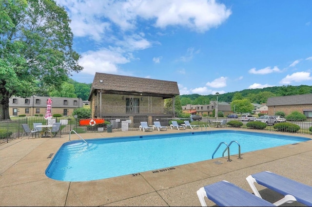 community pool with a patio area and fence