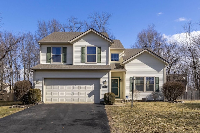 traditional home with driveway, a shingled roof, an attached garage, fence, and a front lawn