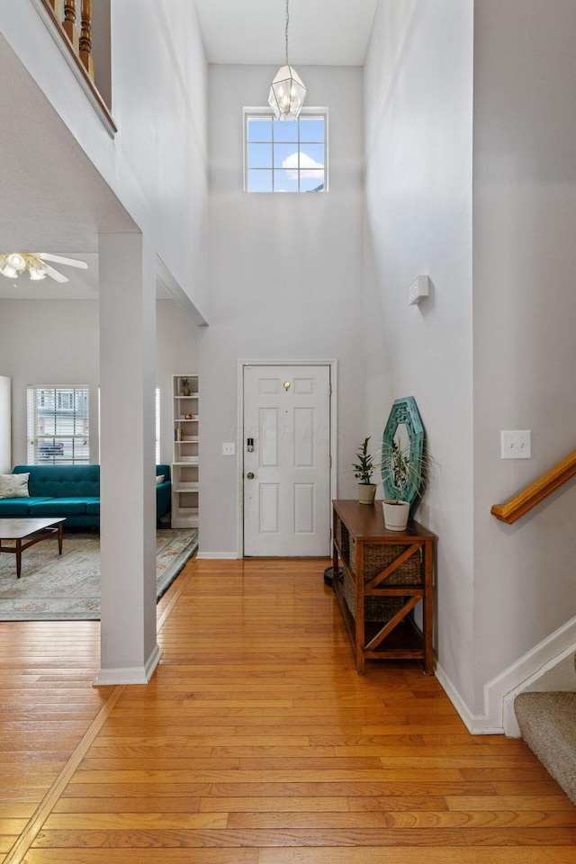 entryway with light wood-style flooring, a high ceiling, stairway, and baseboards