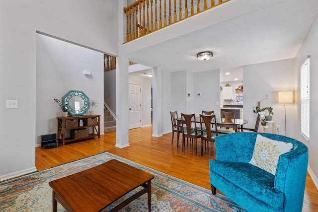 living room with a high ceiling, stairway, baseboards, and wood finished floors