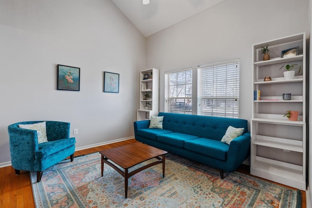 living area featuring lofted ceiling, baseboards, and wood finished floors