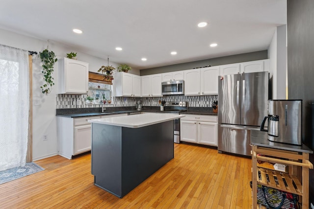 kitchen with light wood finished floors, appliances with stainless steel finishes, and tasteful backsplash