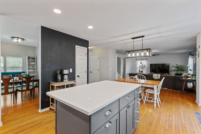 kitchen with light wood-style flooring, gray cabinets, light countertops, and open floor plan