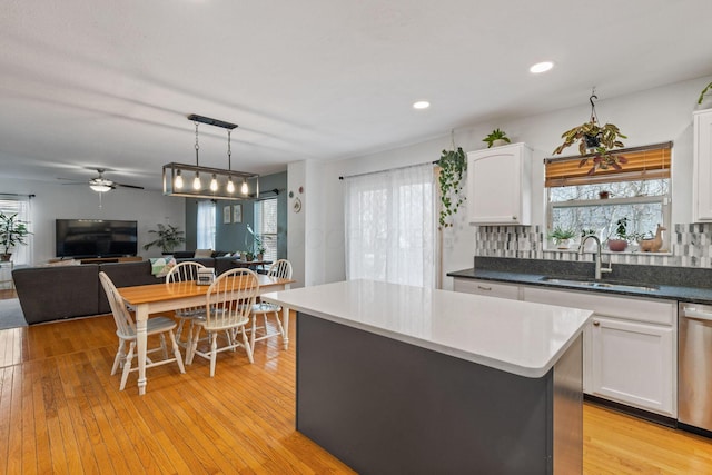 kitchen with dishwasher, light wood-type flooring, a sink, and white cabinetry