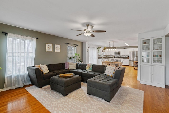 living area with light wood-style floors and ceiling fan