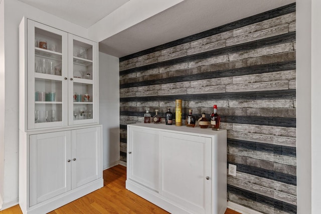 bar with light wood finished floors and wooden walls