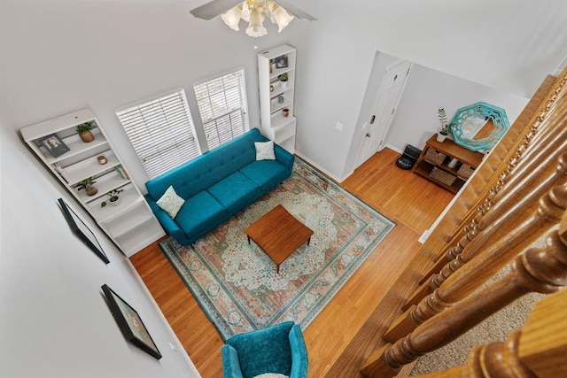 living area with baseboards, a ceiling fan, and wood finished floors