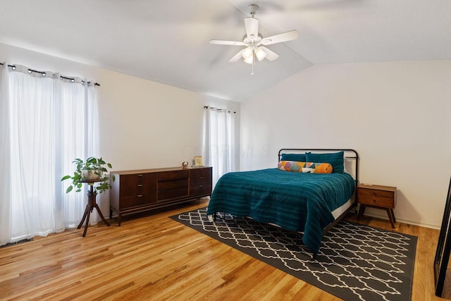 bedroom with vaulted ceiling, visible vents, light wood-type flooring, and a ceiling fan