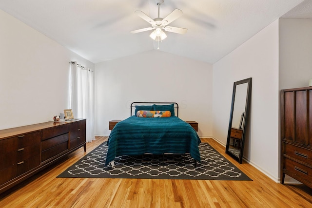 bedroom featuring light wood-type flooring, lofted ceiling, baseboards, and a ceiling fan