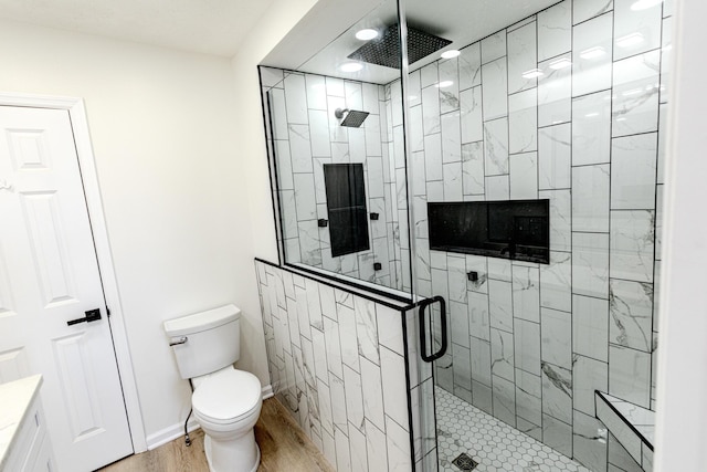 full bath featuring baseboards, a shower stall, toilet, and wood finished floors