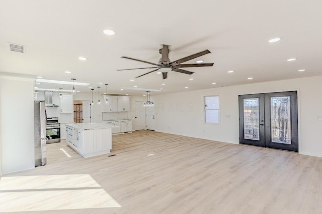 kitchen with range hood, visible vents, light wood-style flooring, appliances with stainless steel finishes, and white cabinetry