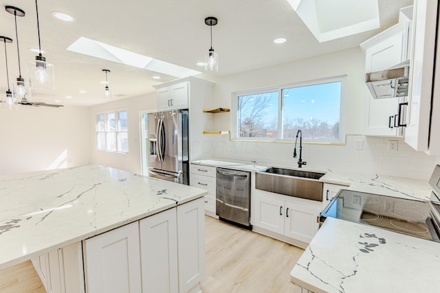 kitchen featuring tasteful backsplash, light wood-style flooring, light stone counters, stainless steel appliances, and a sink