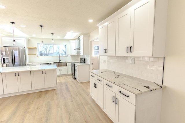 kitchen with stainless steel appliances, light wood-type flooring, a sink, and white cabinets