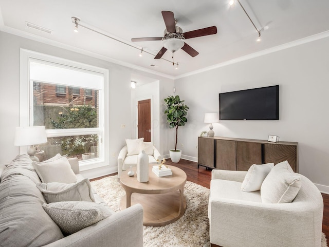 living area with visible vents, ornamental molding, dark wood-type flooring, ceiling fan, and baseboards