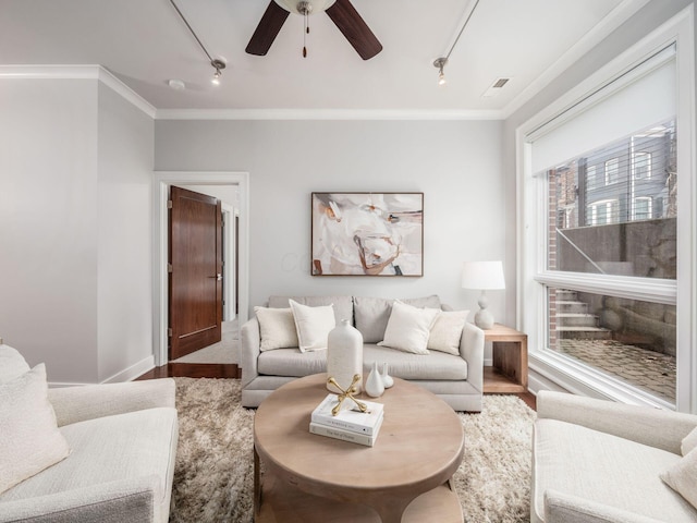 living room featuring rail lighting, visible vents, ornamental molding, wood finished floors, and baseboards