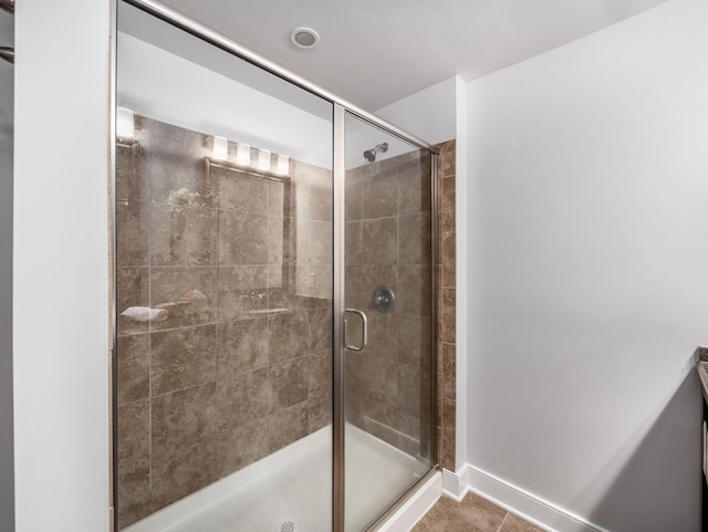 full bath with a stall shower, tile patterned floors, and baseboards