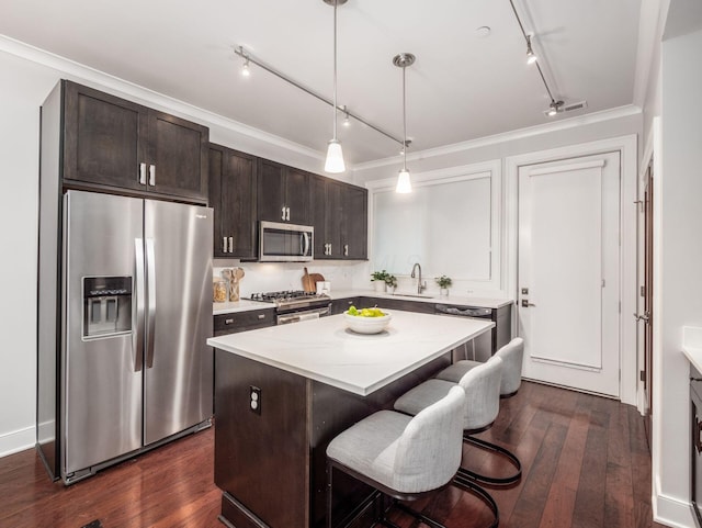 kitchen with a sink, a kitchen island, dark brown cabinets, appliances with stainless steel finishes, and dark wood finished floors