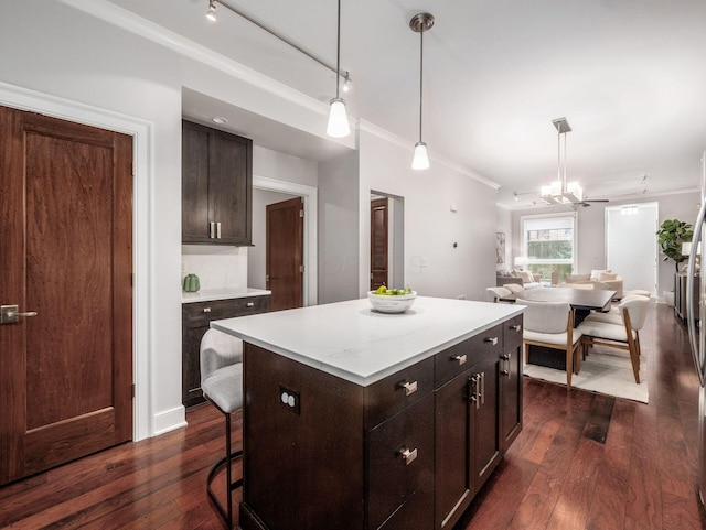 kitchen with dark wood-style floors, decorative light fixtures, a center island, light countertops, and crown molding