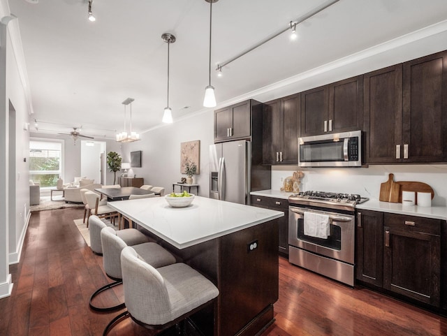 kitchen with stainless steel appliances, open floor plan, light countertops, dark wood-style floors, and a kitchen bar