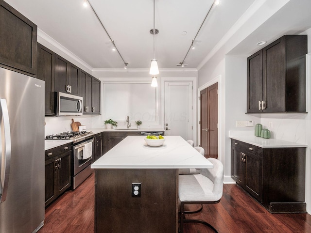 kitchen with stainless steel appliances, dark wood-style flooring, a kitchen island, and a kitchen bar