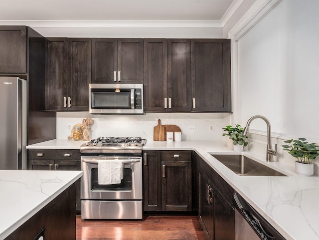 kitchen with stainless steel appliances, a sink, backsplash, light stone countertops, and dark wood finished floors