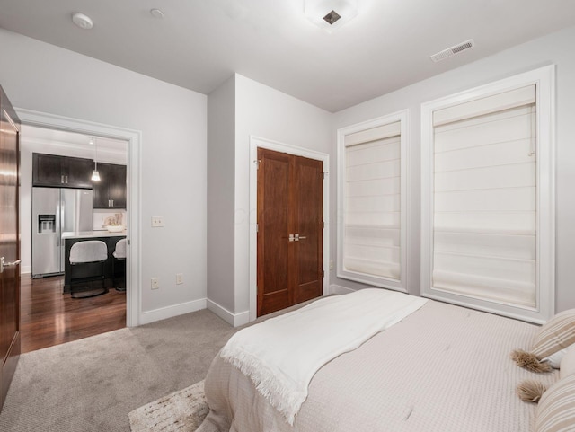 carpeted bedroom featuring visible vents, stainless steel refrigerator with ice dispenser, and baseboards