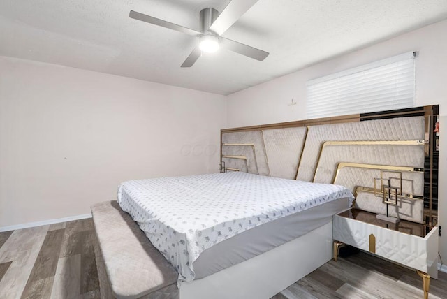 bedroom with ceiling fan, wood finished floors, and baseboards