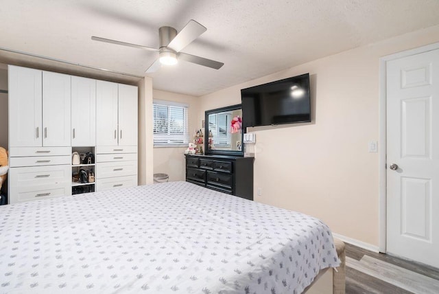 bedroom featuring ceiling fan, a textured ceiling, baseboards, and wood finished floors