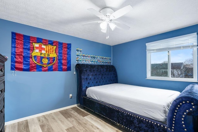 bedroom with ceiling fan, a textured ceiling, baseboards, and wood finished floors