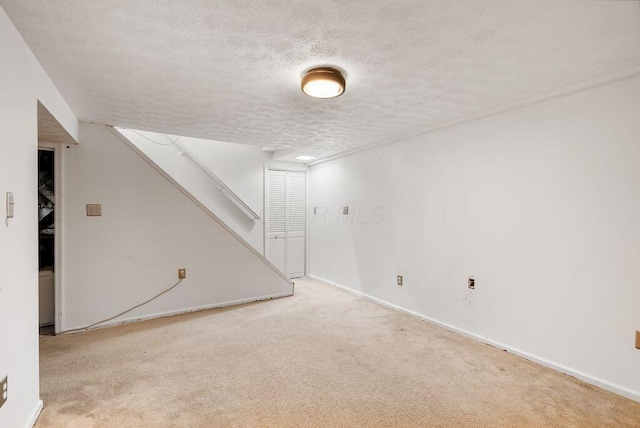 finished below grade area featuring carpet floors, stairway, a textured ceiling, and baseboards