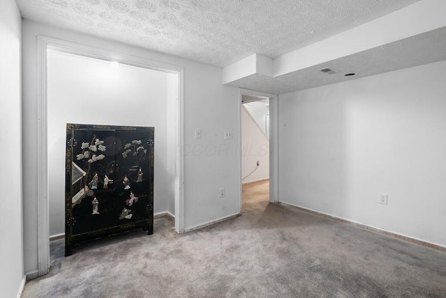 unfurnished living room featuring carpet floors, a textured ceiling, and baseboards