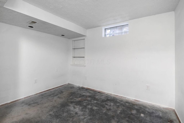 carpeted empty room with a textured ceiling, visible vents, and baseboards