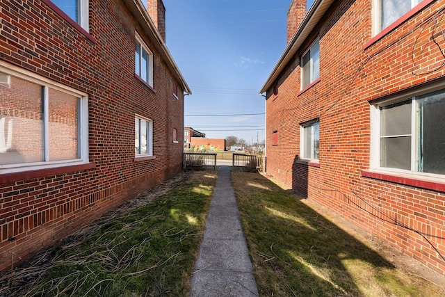 view of side of property featuring a yard, fence, and brick siding