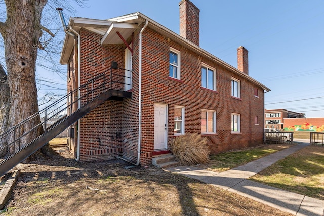 view of side of home featuring entry steps, brick siding, and a chimney