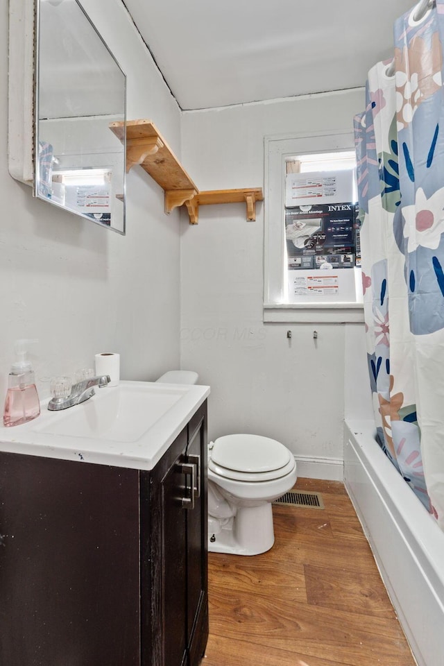 bathroom with toilet, wood finished floors, vanity, visible vents, and shower / bathtub combination with curtain