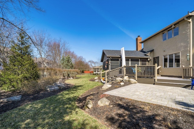 view of yard with a deck, a patio, and a sunroom