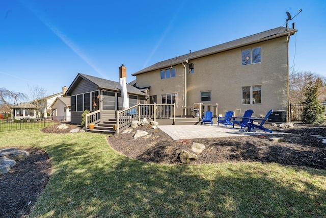 back of house with stucco siding, a lawn, fence, a sunroom, and a patio area