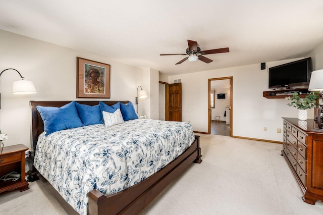 bedroom featuring ensuite bath, light colored carpet, baseboards, and ceiling fan