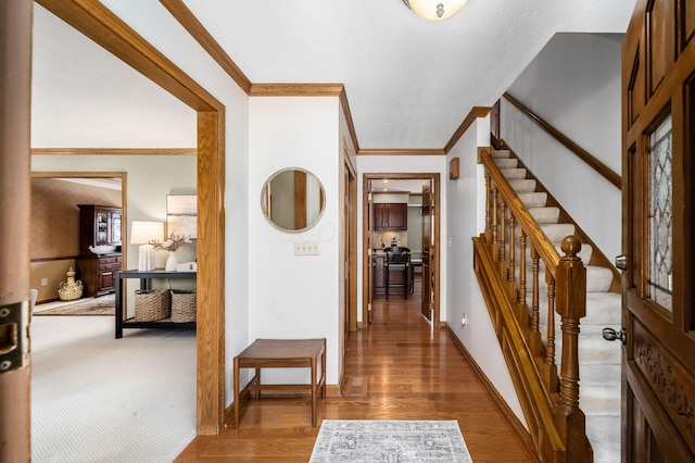 hallway featuring stairway, crown molding, baseboards, and wood finished floors