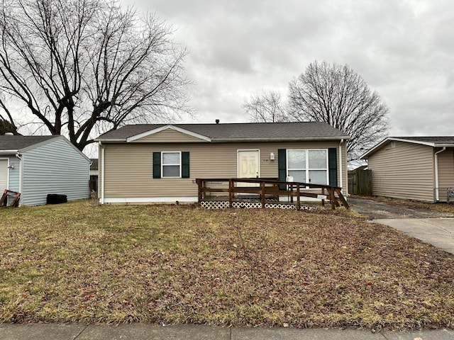 view of front of property featuring a front lawn, a shingled roof, and a wooden deck