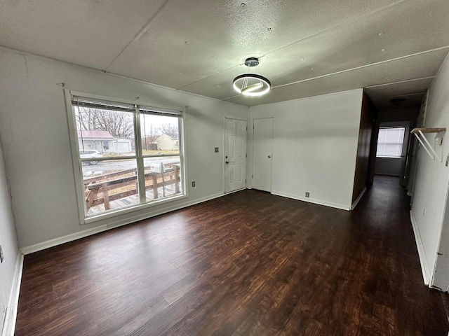 unfurnished room featuring a textured ceiling, baseboards, and wood finished floors