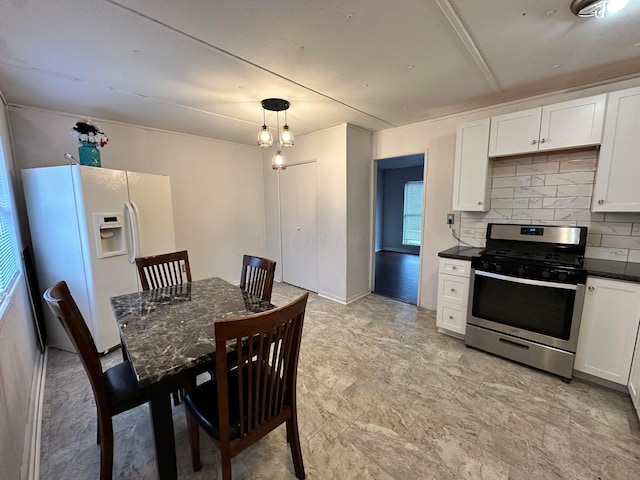 kitchen featuring dark countertops, decorative backsplash, white cabinets, white fridge with ice dispenser, and stainless steel gas range oven