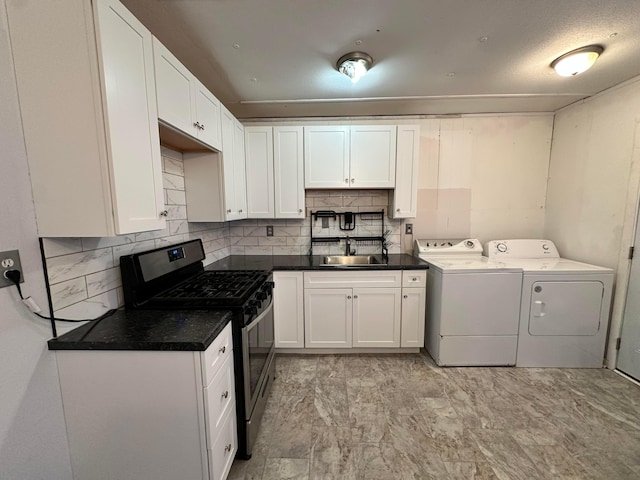 kitchen with tasteful backsplash, dark countertops, stainless steel gas range, washer and dryer, and white cabinetry