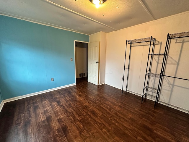 unfurnished bedroom with a textured ceiling, wood finished floors, visible vents, and baseboards