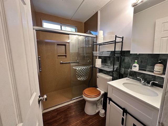 bathroom with toilet, wood finished floors, vanity, a shower stall, and tile walls