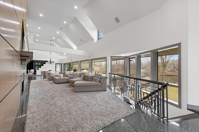 living area with recessed lighting, plenty of natural light, high vaulted ceiling, and granite finish floor