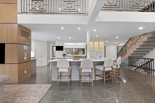 kitchen featuring light countertops, recessed lighting, a towering ceiling, granite finish floor, and white cabinets