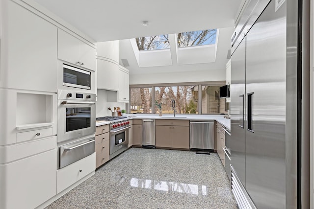 kitchen with a warming drawer, high quality appliances, granite finish floor, and light countertops