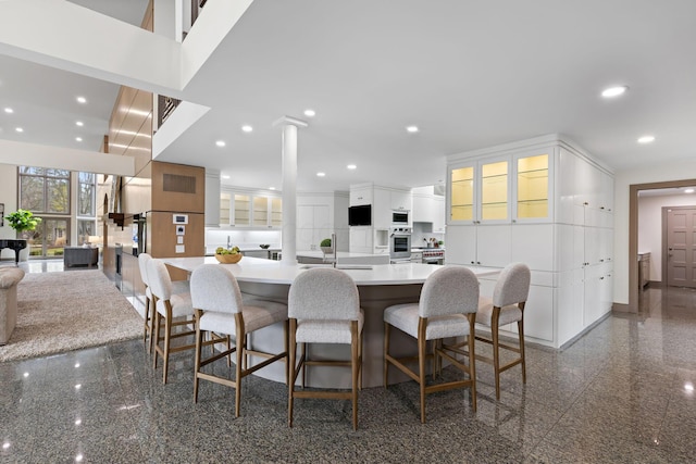 kitchen featuring a sink, white cabinetry, recessed lighting, granite finish floor, and built in microwave