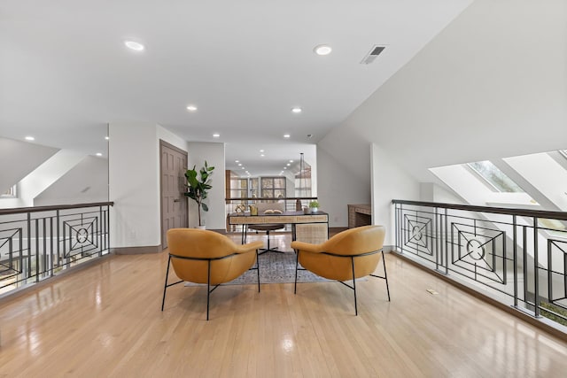 sitting room featuring recessed lighting, visible vents, vaulted ceiling with skylight, and wood finished floors